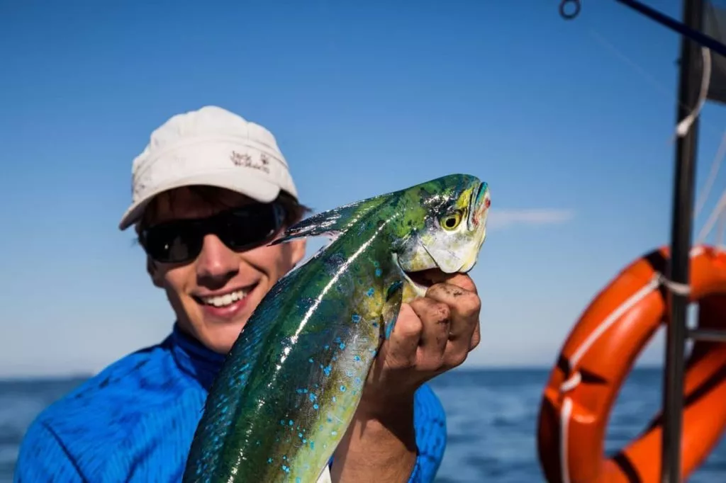 Pescatore con in mano un pesce durante una battuta di pesca