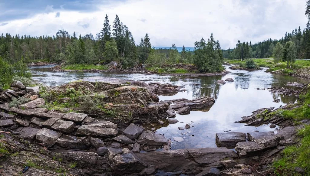 Namsen is one of the longest rivers in Trondelag county, in the central part of Norway and a favorite hunting ground for anglers. Panoramic view of the rocky riverbank on a rainy summer day